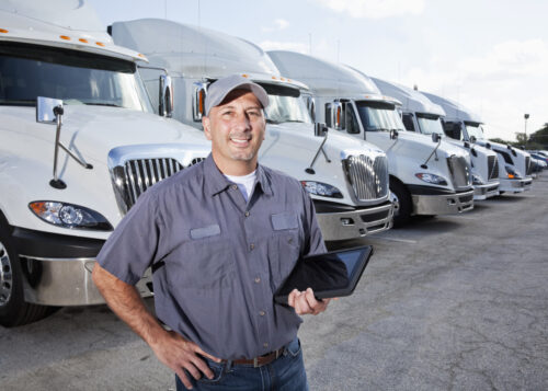 Man holding tablet and standing in front of fleet of white trucks